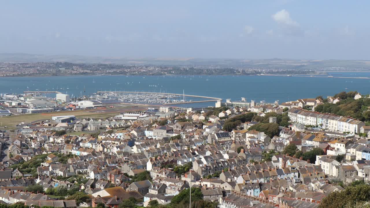Drone video captures Torquay Harbour's marina, bridge, and expansive bay view. The sweeping shot showcases colorful rooftops and serene waters, offering a stunning sky perspective