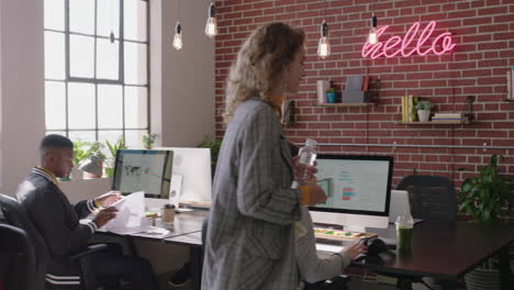 stylish redhead business woman team leader working with colleague pointing at screen sharing ideas enjoying teamwork in successful startup marketing company office