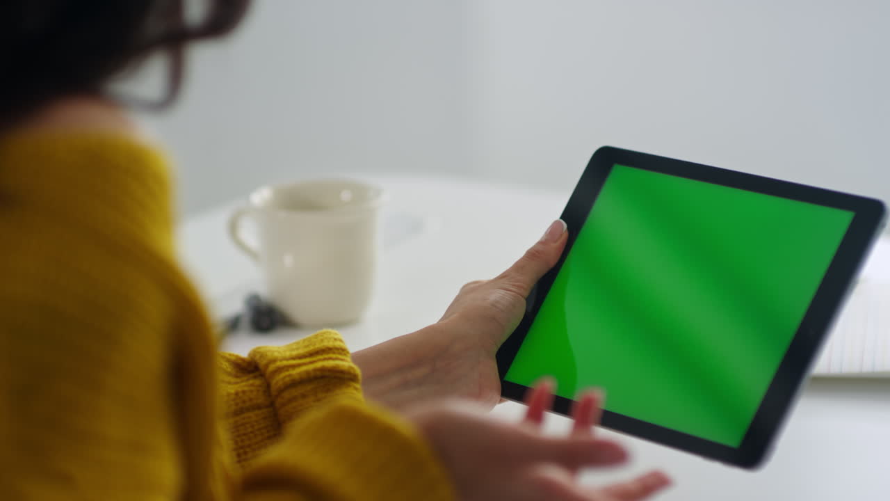 mujer freelance haciendo una videollamada en una tableta de pantalla verde.