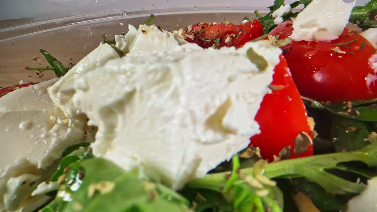 Friske tomater, cremede stykker ost og krydret rucola skaber et levende nærbillede af en salat i middelhavsstil med flotte farver, blanke teksturer og appetitlige detaljer med krydderurter.