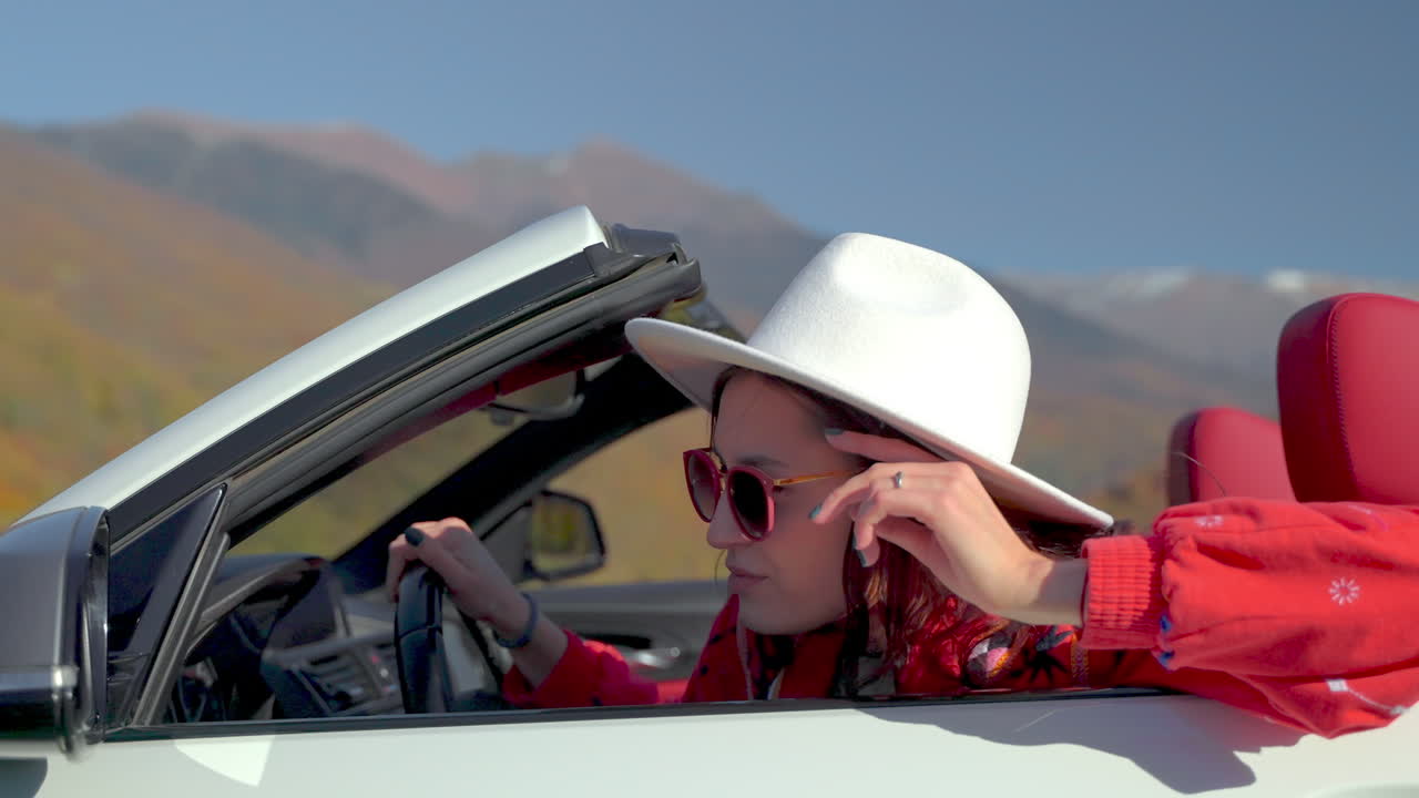mujer conduciendo un descapotable a través de las pintorescas montañas de otoño