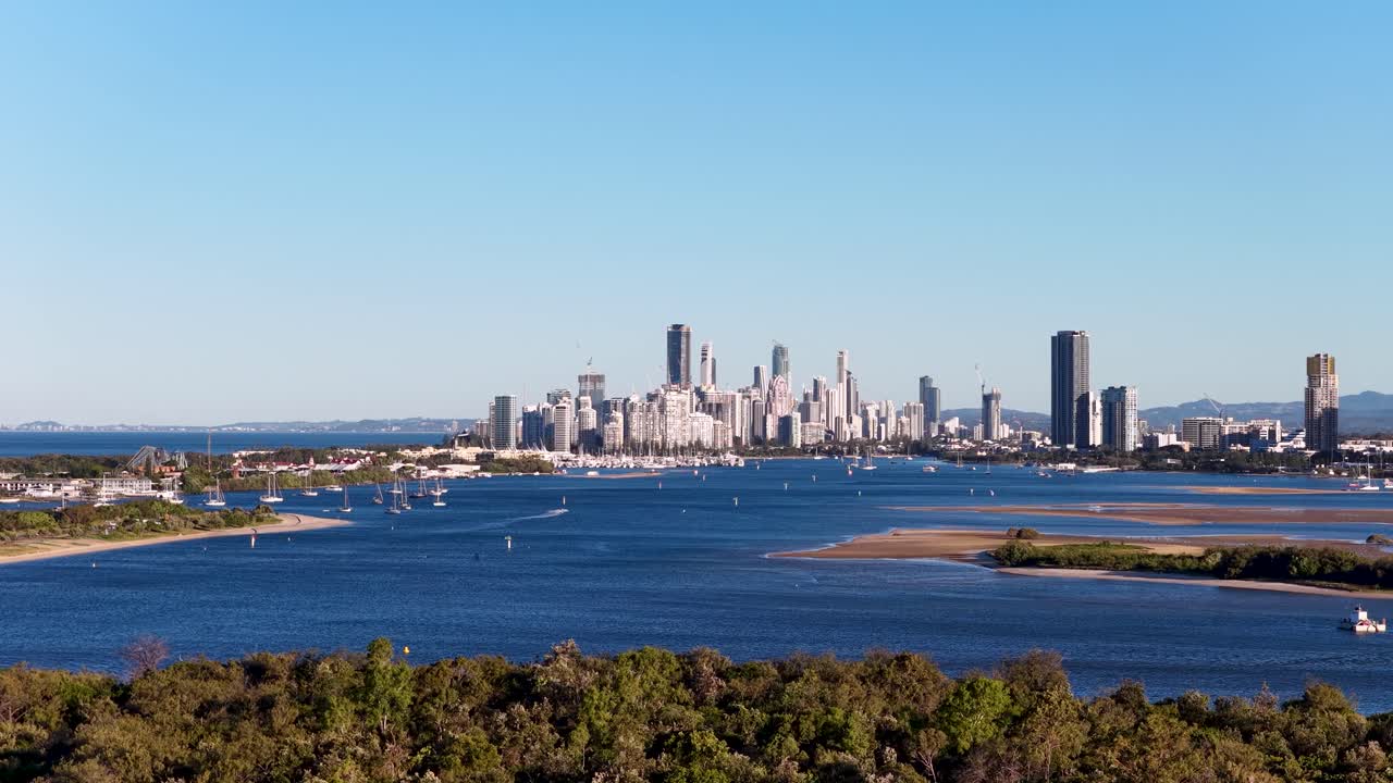 Drone captures panoramic view of Gold Coast skyline and waterways under clear skies, showcasing vibrant urban landscape and natural beauty
