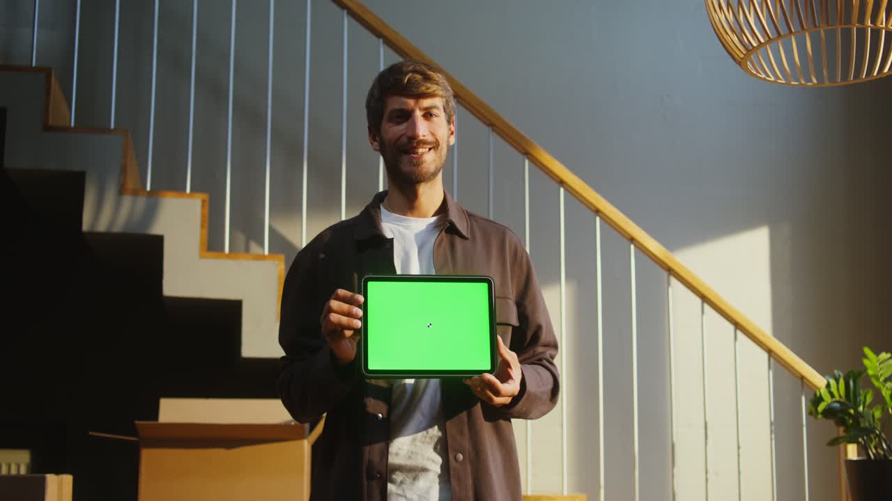 hombre sosteniendo una tableta con pantalla verde en un nuevo hogar