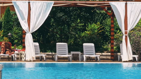people sitting by the poolside of a resort swimming pool during summer holiday