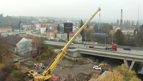 grúa móvil cargando el segmento del puente en un camión en movimiento en la carretera de la ciudad