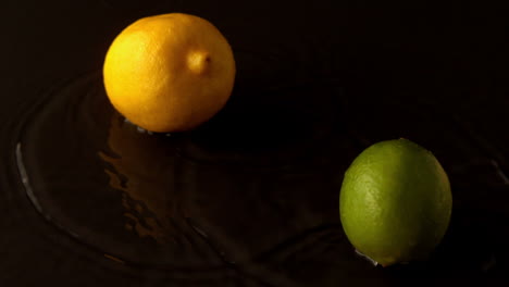 limón y lima cayendo sobre una superficie negra húmeda
