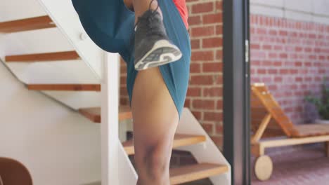 Fit-african-american-man-exercising-at-home-and-doing-stretching-at-home