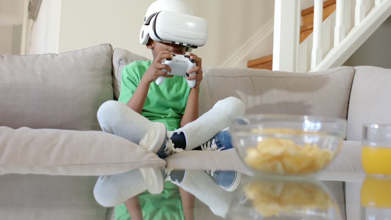 Sta iniziando un gioco VR, un bambino sta regolando il controller mentre si appoggia sul divano per giocare, con delle patatine vicine.