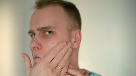 close up of young man touching and checking his face