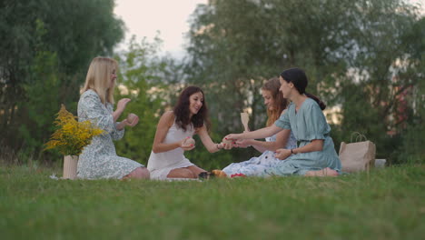 a group of young women in nature in the park hold a master class in clay modeling. joint activity communication laughter common hobby women's circle creative activities.