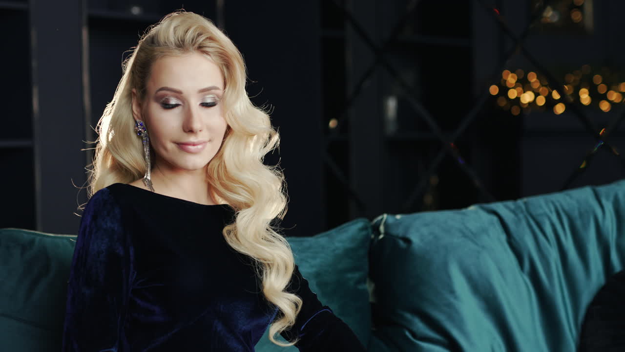 소파에 앉아 카메라를 위한 세련된 금발 포즈