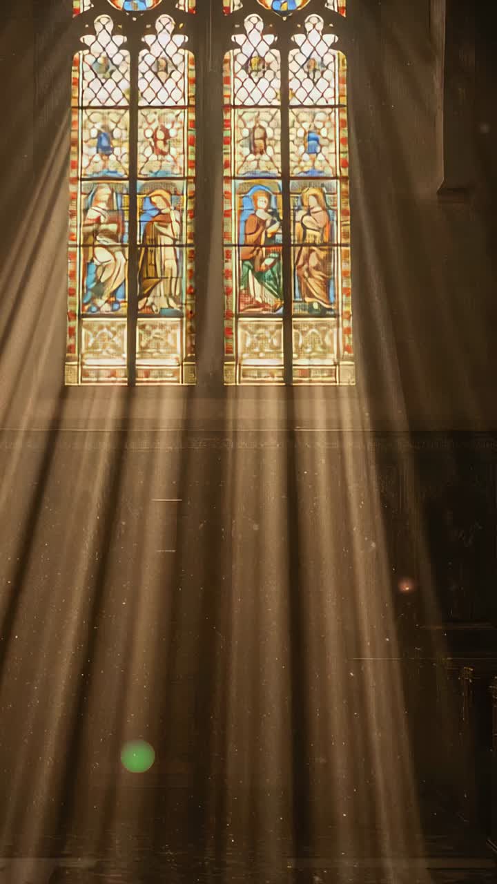 Vertical video: Sun moving through stained glass window into nave, showing motes and green flare
