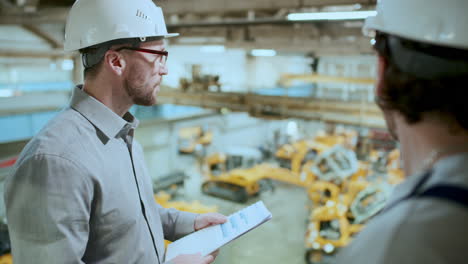 factory technician discussing industrial machinery with engineer