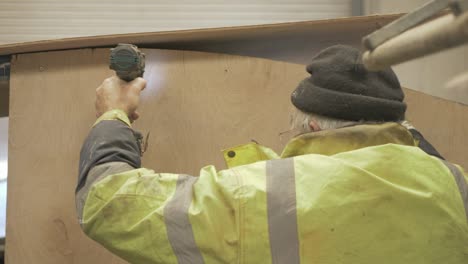 carpintero perforando agujeros en el mamparo de madera contrachapada en la timonera del barco reparado