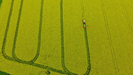 Vuelo-De-Drones-Sobre-El-Campo-De-Canola-En-Polonia-Cuando-El-Rociador-De-Tractor-Agrícola-Rocía-Fungicidas-Y-Pesticidas,-Insecticidas,-Vista-Aérea