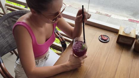 mujer disfrutando de una bebida púrpura en un café al aire libre