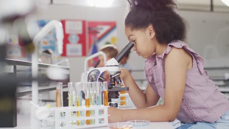 video de una chica biracial feliz con un microscopio durante la lección