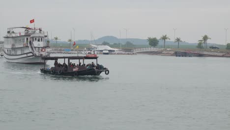 A-small-brown-ferry-boat-is-sailing-towards-the-dock-in-Ha-Long-Bay,-Vietnam