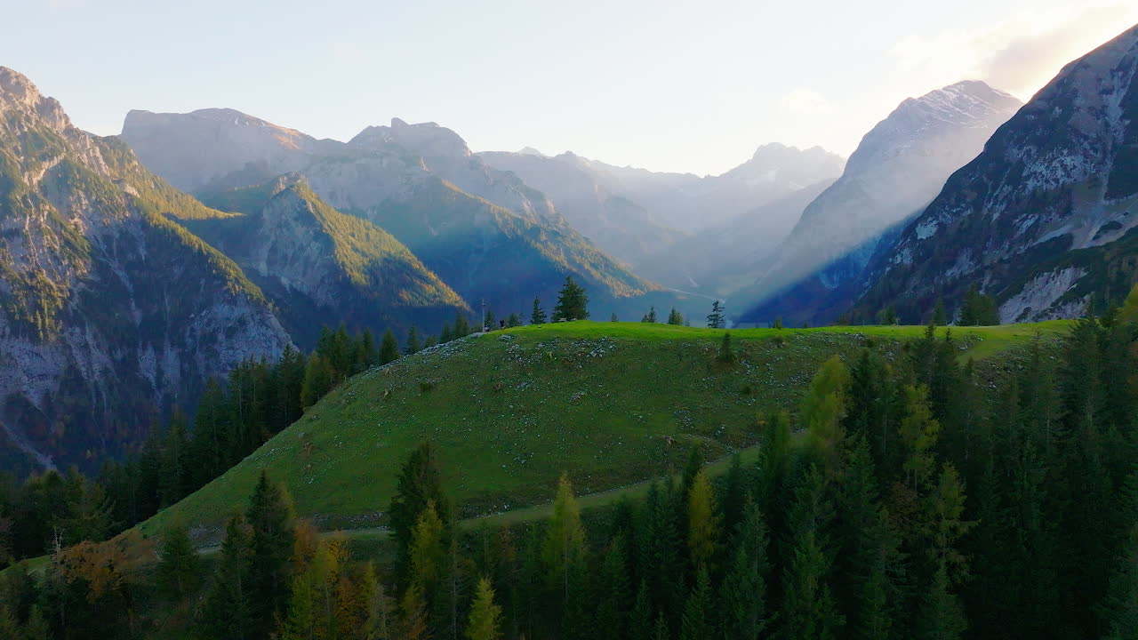Verschleierte Sonnenstrahlen über den bewaldeten Bergen des Karwendelparks, Österreich. Luftaufnahme, die sich vorwärts bewegt.