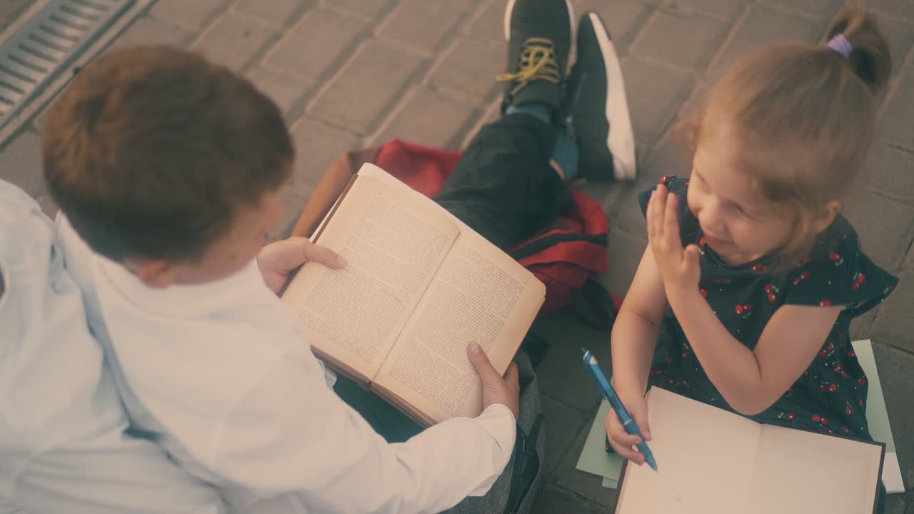 소녀는 코피북에서 그림을 그립니다. 형제들은 거리에서 숙제를 합니다.