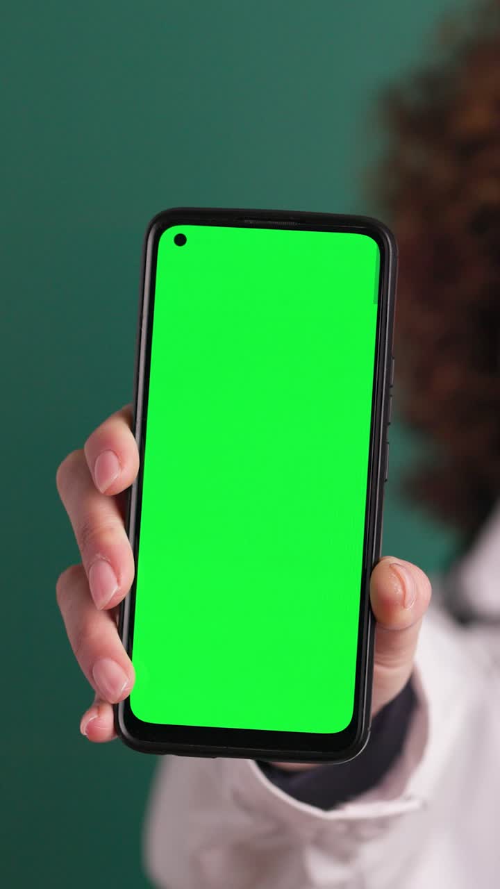 Dottoressa felice che mostra un chromakey sullo smartphone. Filmato verticale
