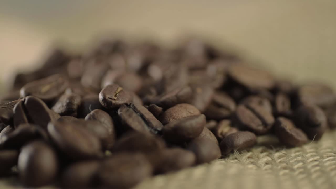 Fresh roasted coffee beans on hessian background panning shot
