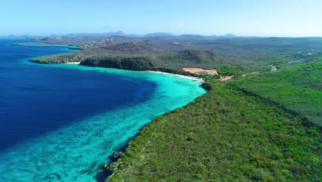 High-angle-panoramic-wide-view-of-stunning-deep-blue-turquose-cove-beach-in-curacao