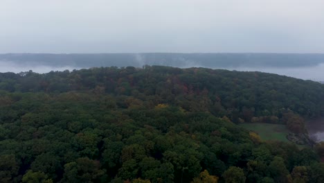 deslizamiento aéreo sobre la cima de inwood hill en la ciudad de nueva york hacia un río hudson brumoso con las empalizadas de nueva jersey en la distancia y un barco en el río