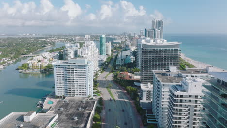 Aerial-panoramic-view-of-modern-urban-neighbourhood-on-seaside-with-tall-buildings.-Tilt-down-on-multilane-road-and-intersection.-Miami,-USA