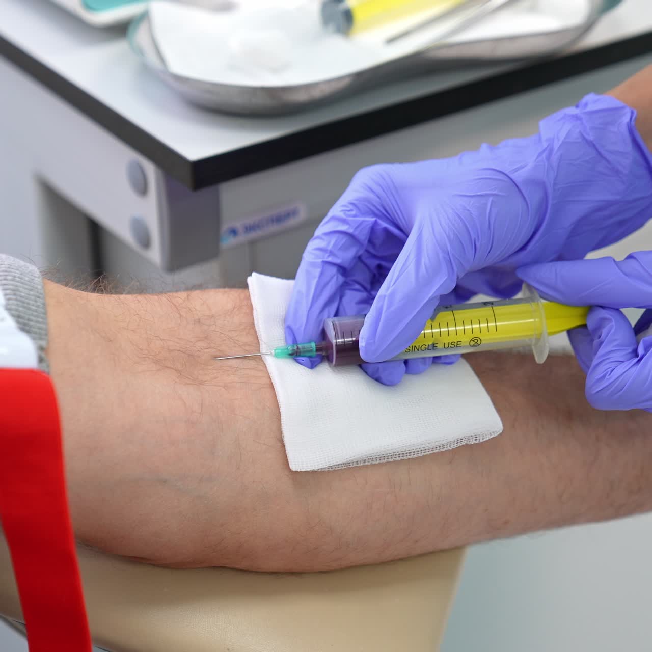 Nurse's hands in gloves input syringe into vein of a patient. Medic takes blood sample of a man. Close up