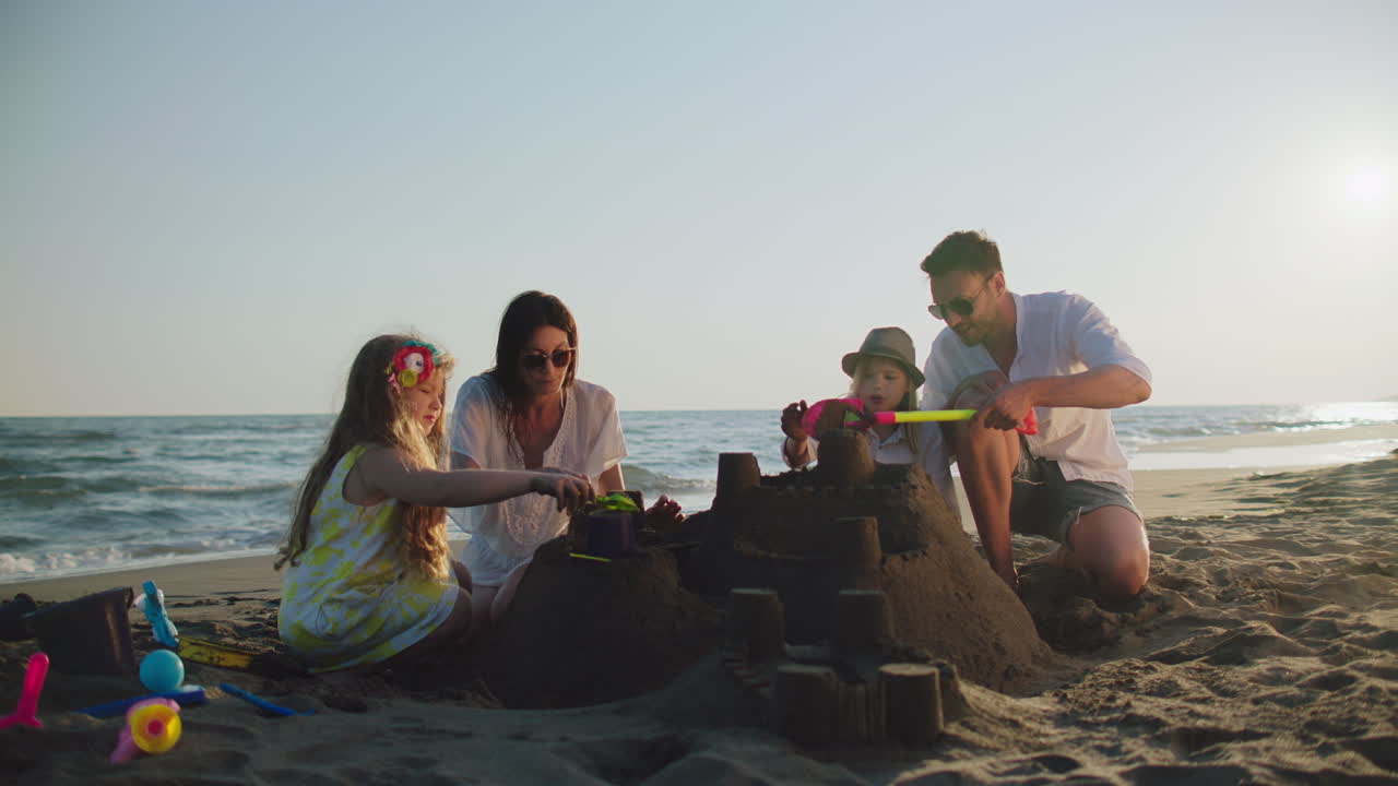 한 가족 이 해변 에 모래 성 을 짓고 있다