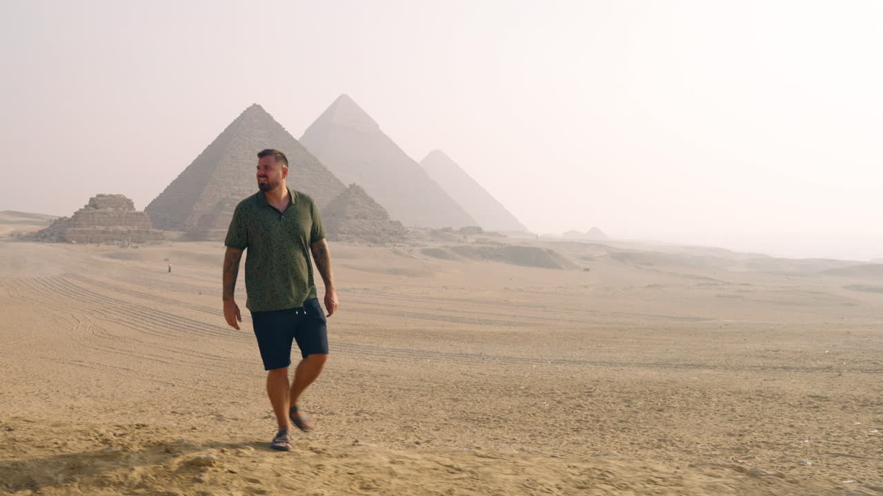 turista caminando en el desierto de arena cerca del complejo de la meseta de giza en giza, egipto.