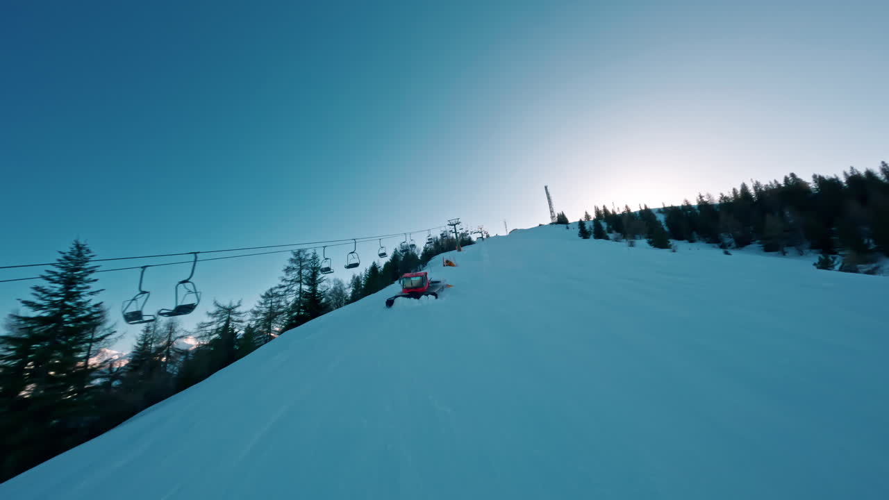 Ski lift ascending a snowy mountain at sunrise with trees lining the slope