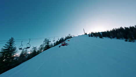ski lift ascending a snowy mountain at sunrise with trees lining the slope