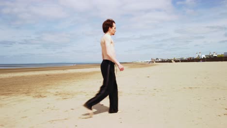 모래 해변에서 셔츠나 신발을 입지 않은 어두운 머리 젊은이, 안테나
