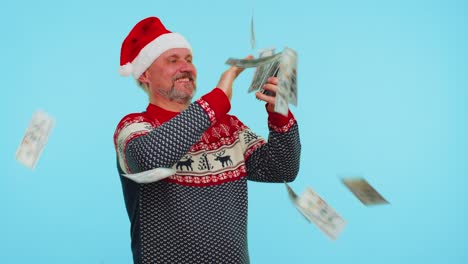 rich man winner in christmas red sweater and hat showing wasting, throwing money around, shopping