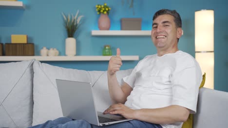 hombre usando una computadora portátil mirando a la cámara y riendo.