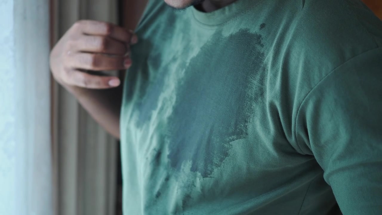 Man Wearing Sweat-Stained Green T-Shirt Standing Indoors