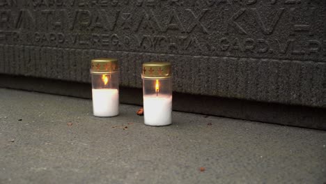 dos velas blancas arden en una tumba de guerra de piedra tallada, un monumento conmemorativo