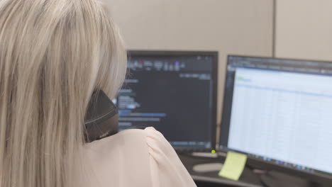 Businesswoman-talking-on-the-phone-and-typing-an-email-in-her-office-slow-motion-unrecognizable