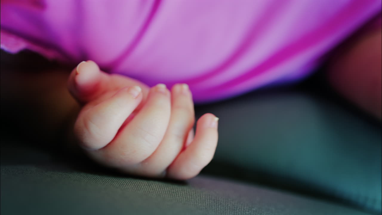 Close up view of a baby's hand and fingers curled in a natural pose while resting