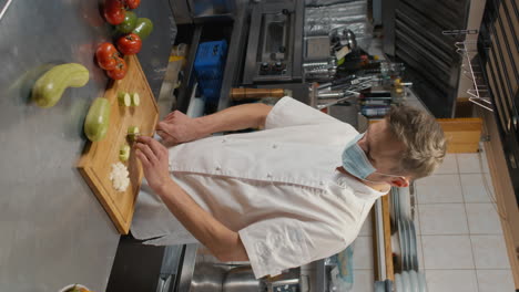 chef in mask cutting zucchini