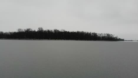 a low fly-over towards a small island of partially frozen creve coeur lake