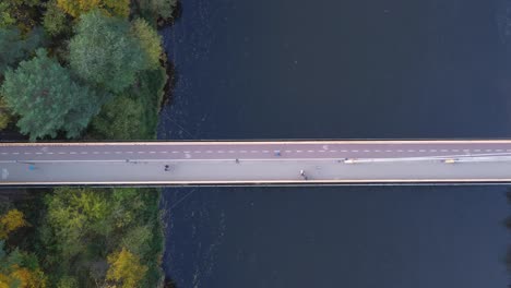 AERIAL-Top-Down-Ascending-Shot-of-a-Bridge-with-Cyclists-and-Pedestrians-in-Vilnius,-Lithuania-during-Autumn