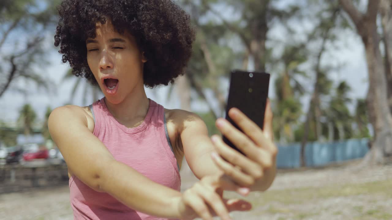 Laughing young girl taking selfie in park