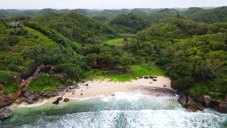 Dronie-shot-of-private-tropical-beach-with-white-sand-that-surrounded-by-forest-and-hill---Indonesia