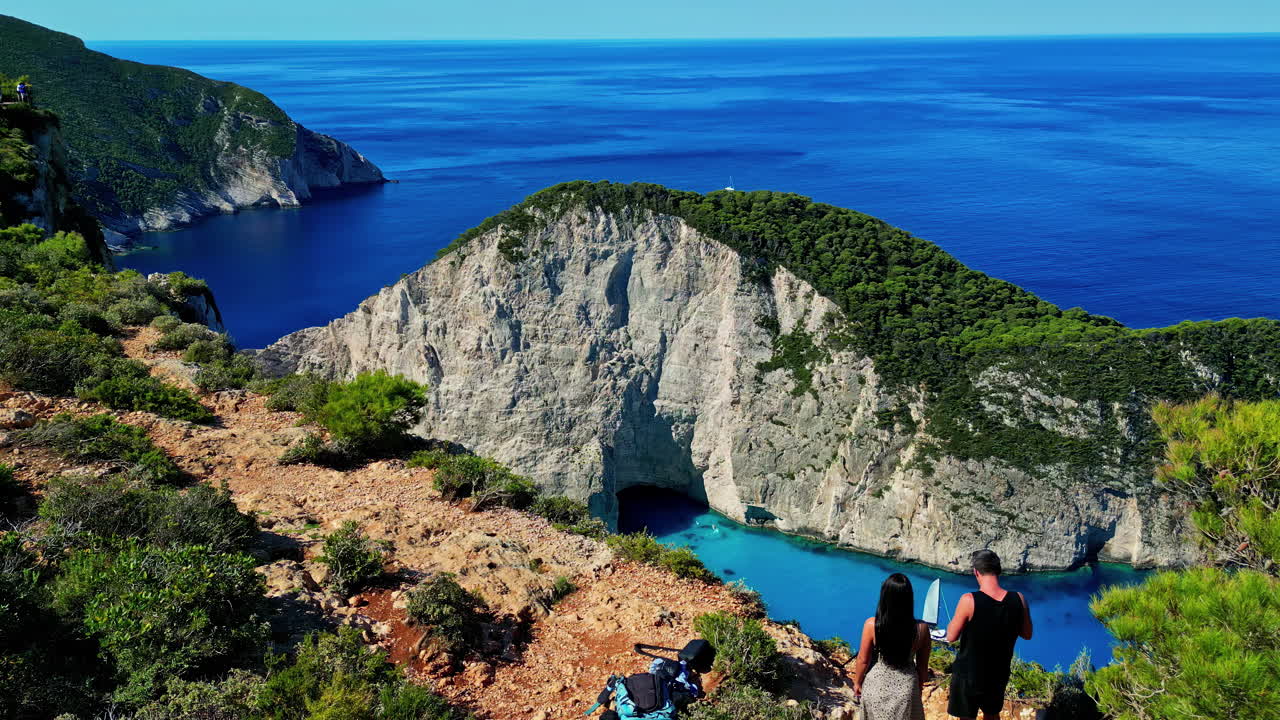 Turister tittar ut över kalkstensklipporna vid Navagio Beach på Zakynthos, Grekland.