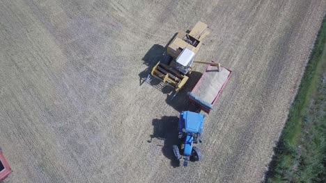 combine harvester unloading grain,tractor trailer carriage, aerial top down view