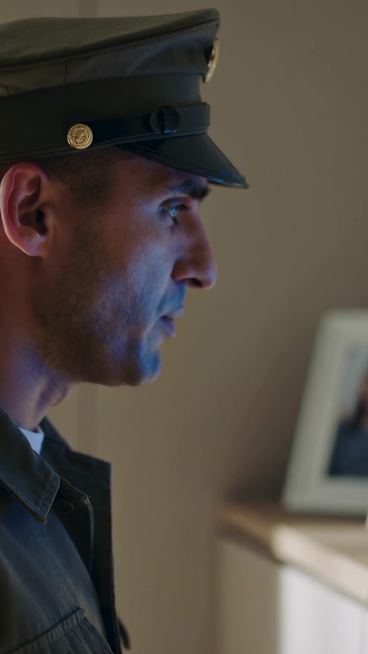 Vertical video: Seeing framed picture, man in peaked cap, uniform mouthing in room under blue fill
