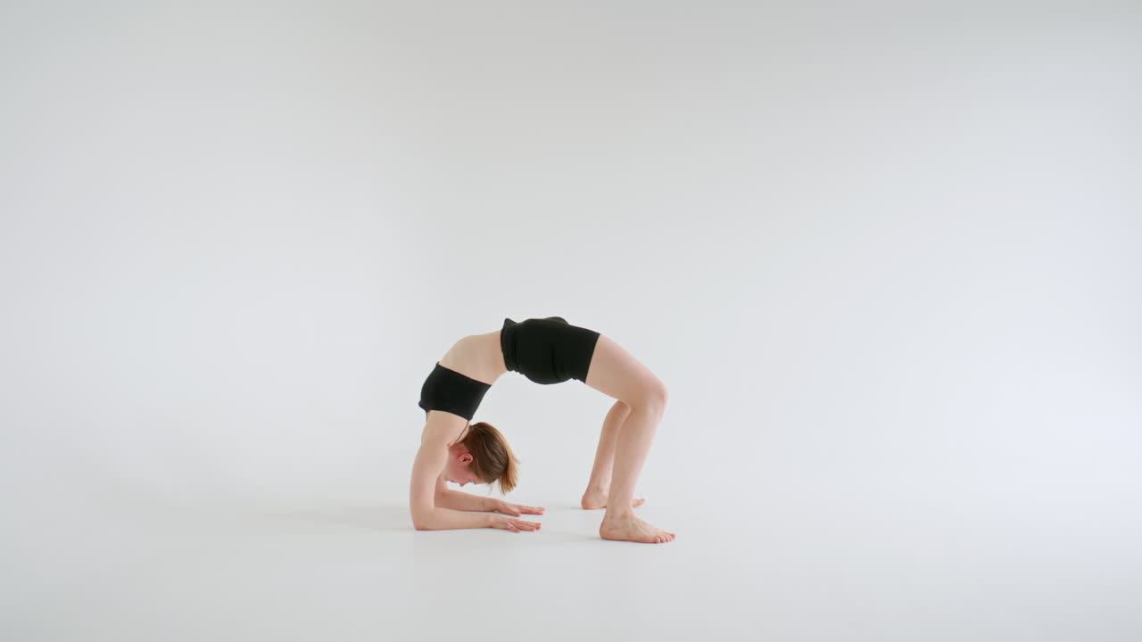 Junge Frau in der Unterarm-Rad-Pose in einem minimalistischen Studio